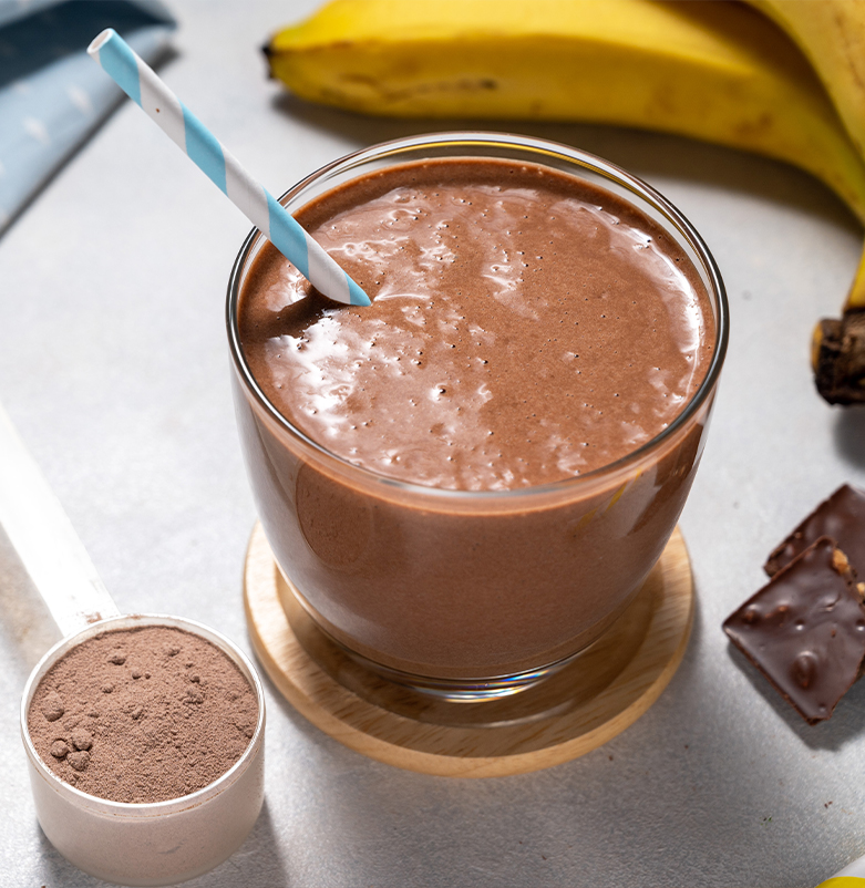 A glass of chocolate smoothie next to a banana