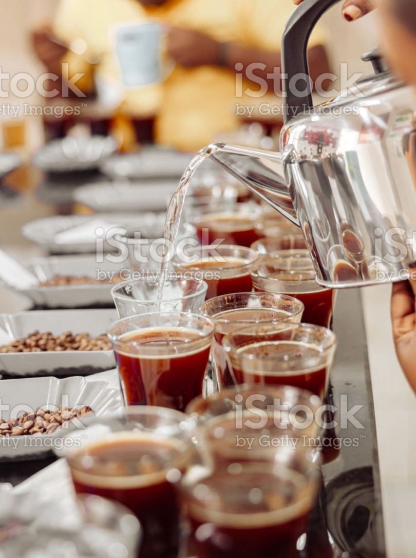 A person pours coffee into cups on a long table