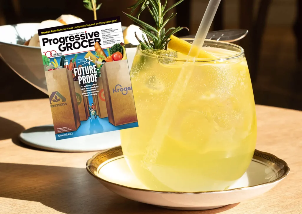 Ice cold lemonade with a straw with a copy of Progressive Grocer magazine