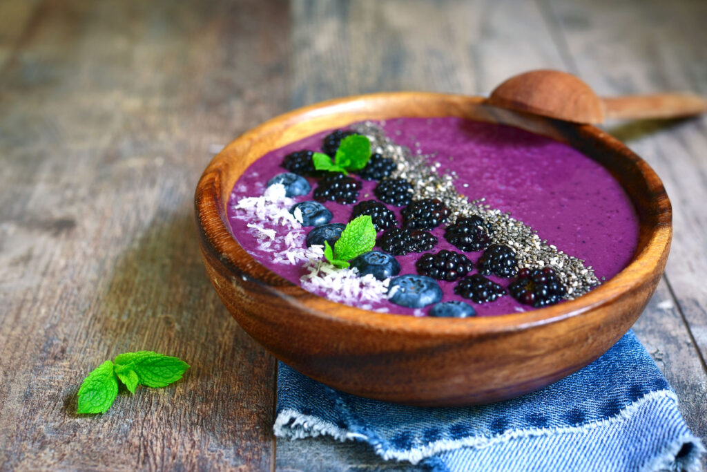a wooden bowl filled with a purple smoothie