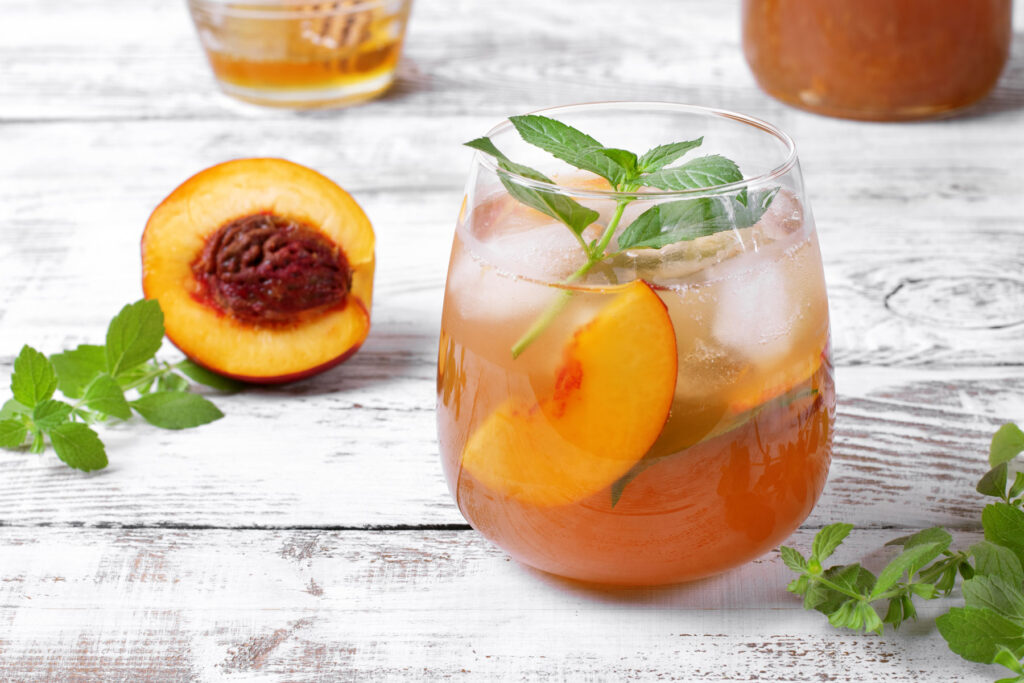 a glass filled with a refreshing drink and a sliced peach