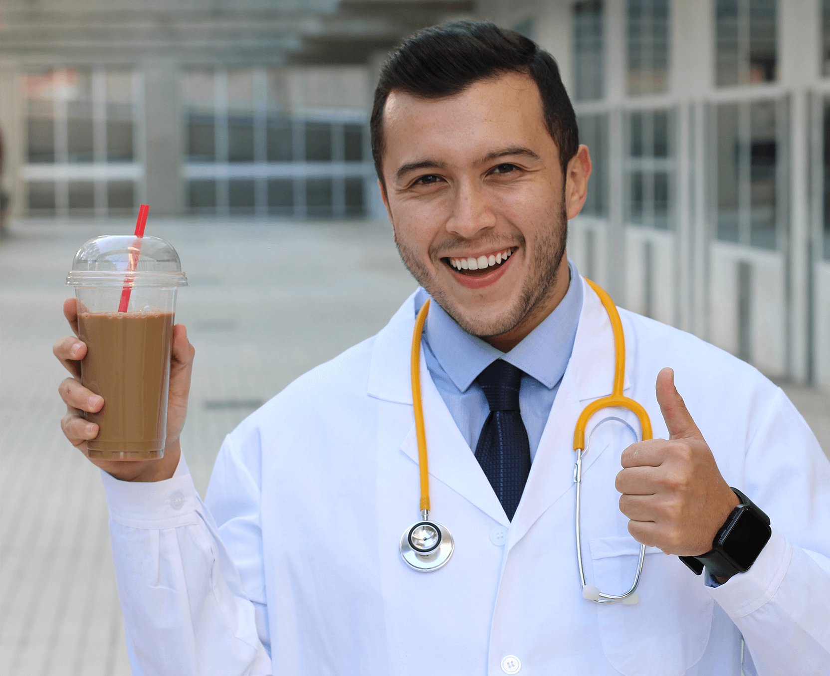 A man in a white lab coat holding a cup of coffee