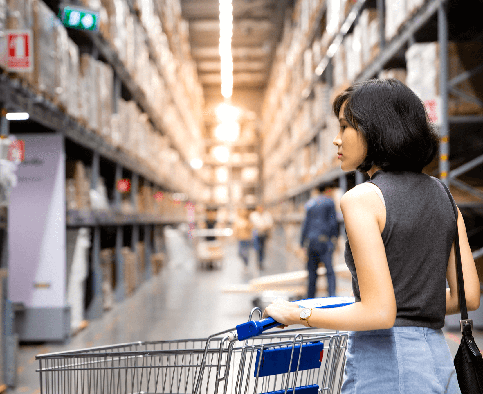 a woman pushing a shopping cart in a warehouse